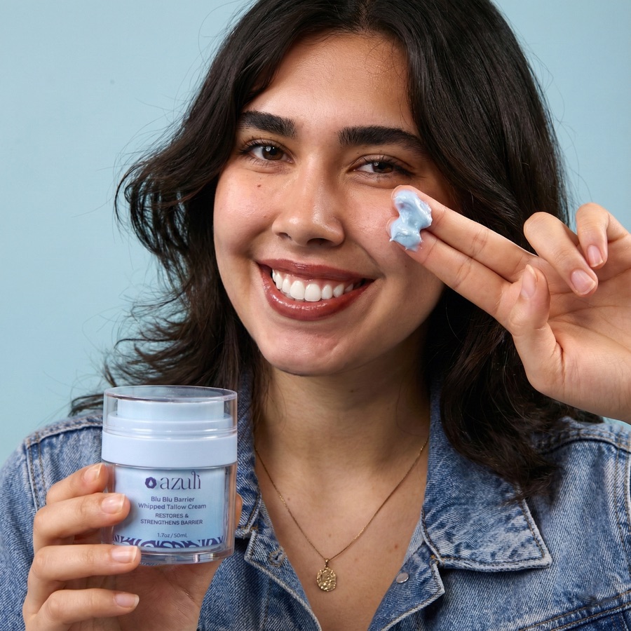 A model holding Blu Blu Barrier and dabbing the blue cream on her cheek